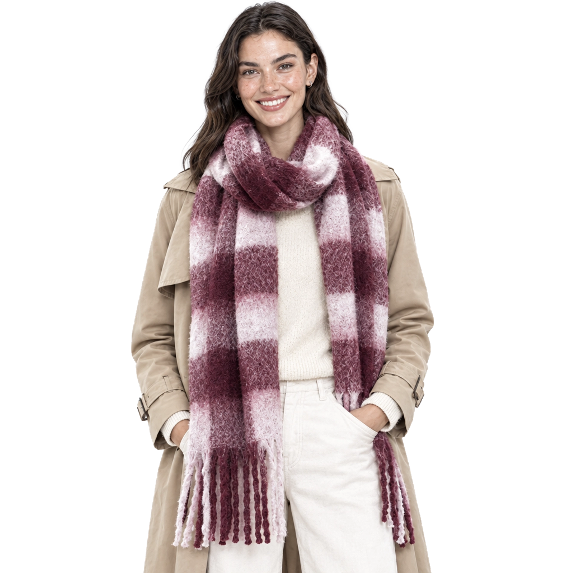 Smiling model with hands in her pockets wearing a Summer & Rose chunky burgundy and pink plaid fringed scarf over a tan trench coat, cream sweater, and cream pants, on a white background.