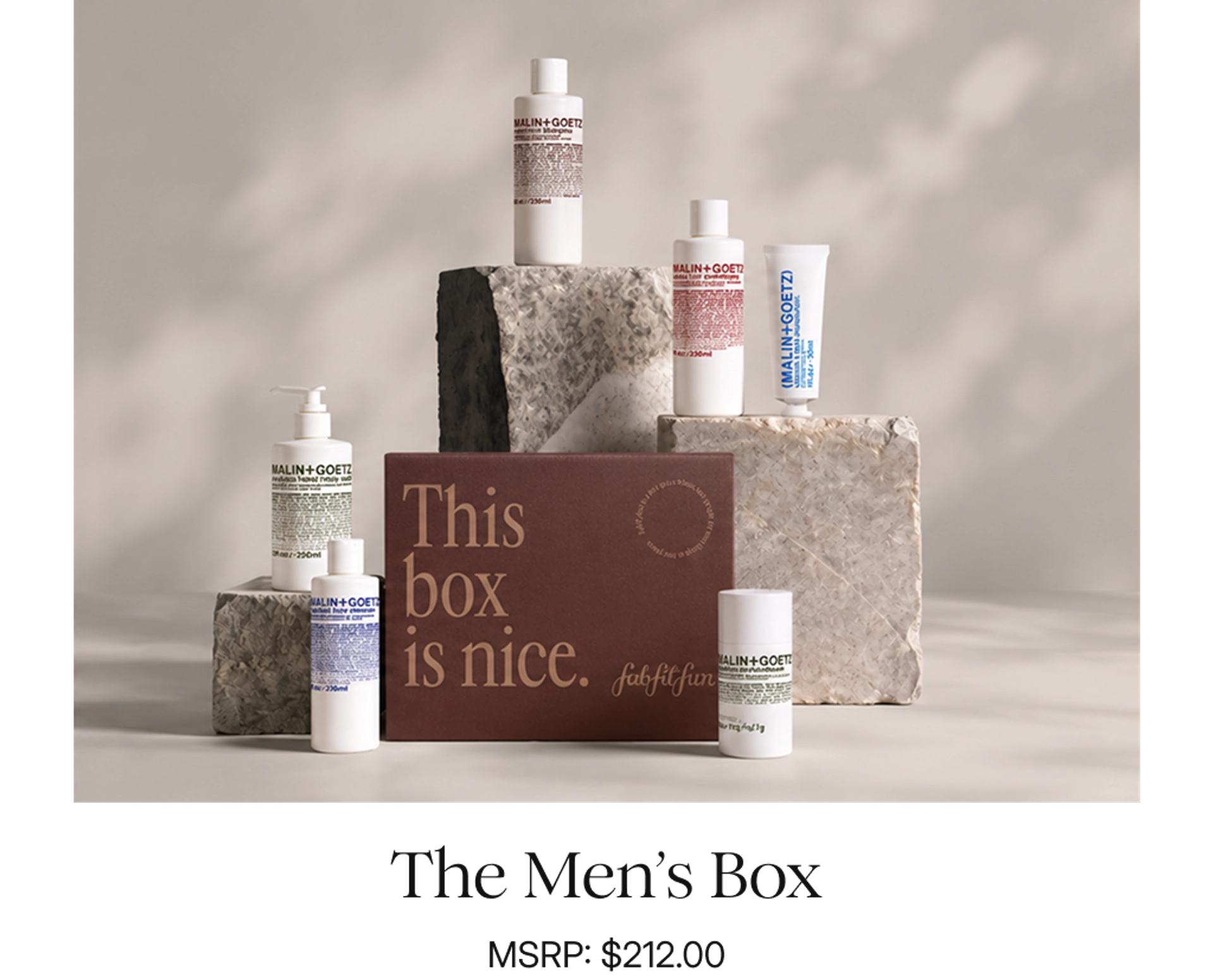 FabFitFun Men's Box, a burgundy box reading "This box is nice," surrounded by white Malin+Goetz grooming products, including peppermint shampoo, conditioner, hand and body wash, face cleanser, moisturizer, and deodorant, displayed on rough stone blocks, with the caption "The Men's Box, MSRP: $212.00."